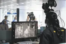  ?? Mohd Rasfan / Agence France-Presse ?? A Malaysian health officer screens arriving passengers with a thermal scanner at Kuala Lumpur Internatio­nal Airport.