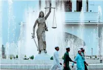  ?? AP file ?? People walk past the statue at the Supreme Court complex in Dhaka, Bangladesh. —