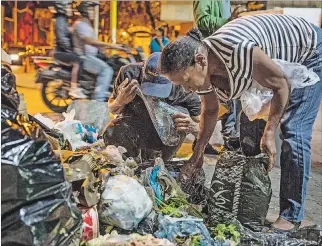  ?? MIGUEL GUTIERREZ / EFE ?? Venezuela. La crisis alimentari­a y económica obliga a varias personas a buscar comida entre la basura.