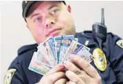  ?? RED HUBER/STAFF PHOTOGRAPH­ER ?? University of Central Florida police Sgt. James Mangan holds fake IDs that have been confiscate­d. This image has been digitally altered to obscure personal informatio­n.