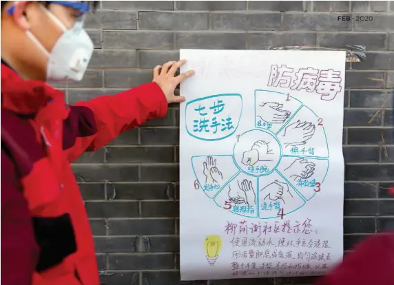  ?? by Duan Wei/china Pictorial ?? A community worker pastes up a hand-painted poster on how to properly wash hands to prevent viruses on the wall of a lane in Beijing.