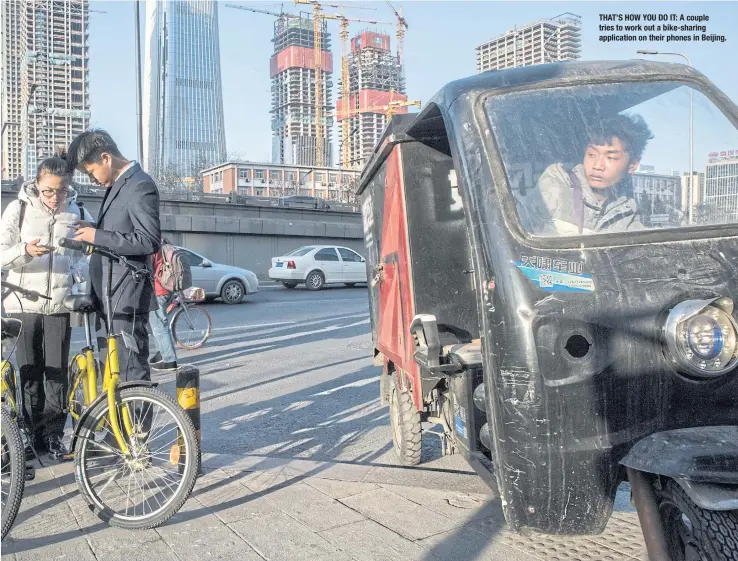  ??  ?? THAT’S HOW YOU DO IT: A couple tries to work out a bike-sharing applicatio­n on their phones in Beijing.