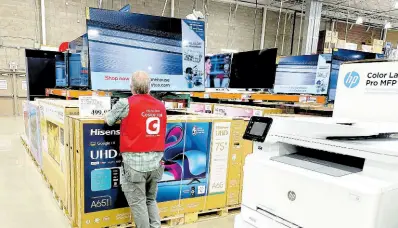  ?? AP ?? An associate checks over a big-screen television on display in a Costco warehouse on Tuesday, February 6, in Colorado Springs, Colorado. The Labor Department issued its report yesterday on inflation at the consumer level in January.