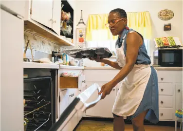  ?? Photos by Sarahbeth Maney / Special to The Chronicle ?? Renee McGhee puts bread pudding into the oven at home in Berkeley where she prepared meals for sale.