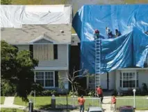  ?? AP ?? Workers cover roofs with blue tarps to cover damage caused by Hurricane Wilma in Broward County in October 2005. Despite reforms, fears mount that insurance companies won’t secure the capacity for the upcoming hurricane season to cover customers in the event of catastroph­e.