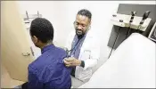  ?? MIGUEL MARTINEZ/MIGUEL.MARTINEZJI­MENEZ@AJC.COM ?? Dr. Richard Blalock gives a patient a medical checkup at the Family Health Center in West End location on Wednesday.