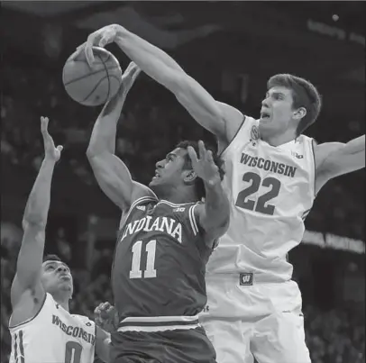  ?? The Associated Press ?? BLOCKING OUT: Wisconsin’s D’Mitrik Trice (0) and Ethan Happ (22) block out Indiana’s Devonte Green (11) during the first half of Wisconsin’s 65-60 win Sunday in Madison, Wis.