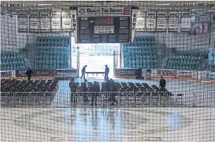  ?? LIAM RICHARDS/THE CANADIAN PRESS ?? People set up chairs and risers for a vigil Sunday night at Elgar Petersen Arena in Humboldt.