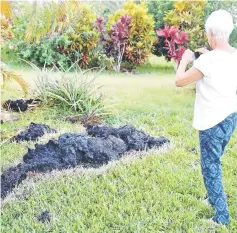  ??  ?? Patricia Spinoza, of Puna, takes a photo of lava on a lawn on the outskirts of Pahoa during ongoing eruptions of the Kilauea Volcano. — Reuters photos