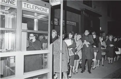  ?? Bild: AP ?? Telefonkio­sken har fått stryka på foten i och med mobilens utveckling. Här en telefonkö i New York 1956 under ett stort strömavbro­tt.