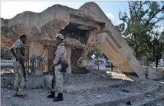  ??  ?? DESTRUCTIV­E: Jubaland security forces stand in front of a destroyed monument to national unity built by former dictator Siad Barre. It was destroyed by al-Shabaab, which controlled Kismayo until 2012.