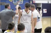  ?? ?? Assistant coach Brady Rockwell (far left) and head coach G.J. Rockwell congratula­te Zach Dubois (21) and Lucas DaCosta as they leave the floor for reserves late in Middletown’s 51-24home win over Fort Bragg.