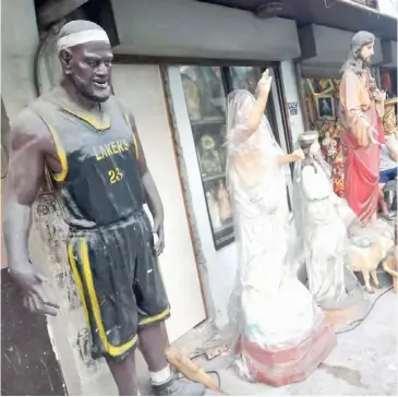  ?? PHOTOGRAPH COURTESY OF PUBLIKO/FB ?? A wood carving of basketball demigod Lebron James is displayed along with religious icons outside a shop in Tayuman Street, Sta. Cruz, Manila.