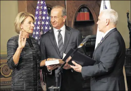  ?? ASSOCIATED PRESS ?? Vice President Mike Pence swears in Education Secretary Betsy DeVos in Washington on Tuesday as DeVos’ husband, Dick, watches. With Pence’s vote, the Senate confirmed DeVos 51-50.