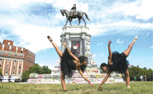  ?? (Julia Rendleman/Reuters) ?? BALLERINAS KENNEDY GEORGE, 14, and Ava Holloway, 14, pose in front of a monument of Confederat­e general Robert E. Lee after Virginia Governor Ralph Northam ordered its removal earlier this month.