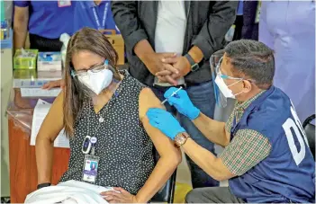  ?? — AFP photo ?? Health Secretary Francisco Duque III (right) administer­s the Sinovac vaccine on Eileen Aniceto, medical doctor of the Lung Center of the Philippine­s, in Quezon City.