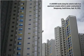  ??  ?? A LABORER works along the exterior wall of an apartment complex which is under constructi­on in Hongseong, South Korea, Sept. 16, 2015.