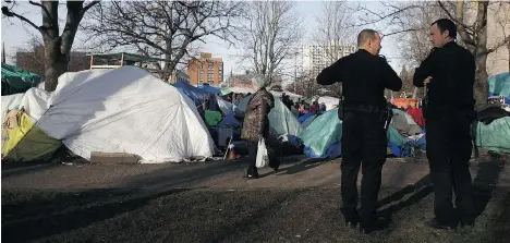  ?? CHAD HIPOLITO/THE CANADIAN PRESS ?? Victoria Police watch over residents at a homeless camp known as InTent City during a block party at the camp in February.