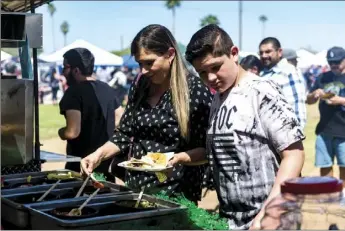  ??  ?? Crystal Goodrum and her son Ricardo Clemente add sauces to their flour Carne Asada tacos during the 2018 Imperial Valley Carne Asada Cook-Off held Saturday afternoon at Stark Field in El Centro. VINCENT OSUNA PHOTO