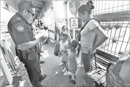  ??  ?? ▲ Un oficial de aduanas de Estados Unidos revisa los documentos de una familia que solicita asilo en ese país. Foto Ap