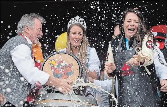  ?? PETER LEE WATERLOO REGION RECORD ?? As the Oktoberfes­t keg was tapped on Friday, Hometown Hockey host Tara Slone, right, held the spigot, allowing beer to spray and pour freely out. Keeper of the keg, Art Primosch slapped his hand over the opening until the spigot could be put in place. Miss Oktoberfes­t 2018 Sandra Dynka is centre.