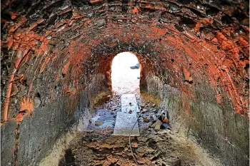  ?? Staff photos by Hunt Mercier ?? ABOVE: The view from the inside of Chris Powell's tsuchigama kiln.
LEFT: Associate professor from Texas Christian University Chris Powell sits next to his tsuchigama kiln and talks about the history of the Japanese kiln on his property in De Queen, Arkansas. The Tsuchigama Project uses a Japanese method of firing pottery objects made from local Arkansas clay.
BELOW: A pottery elephant sits next to the tsuchigama kiln.