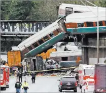  ?? Elaine Thompson ?? Cars from an Amtrak train lay Dec. 18 spilled onto Interstate 5 below alongside smashed vehicles as some train cars remain on the tracks above in Dupont, Wash. Dozens of 911 call recordings released by South Sound 911 Dispatch provide a vivid account...