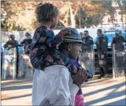  ?? PEDRO PARDO/GETTY-AFP ?? A migrant carries a child past Mexican police Monday outside the Benito Juarez Sports Center in Tijuana, Mexico.
