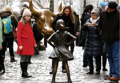  ?? (Brendan McDermid/Reuters) ?? PEOPLE LOOK at a statue of a girl facing the Wall Street Bull in the financial district of New York City last week. The statue is part of a campaign by US fund manager State Street to push companies to put women on their boards.