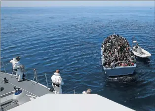  ?? Picture: REUTERS ?? SAFE AT LAST: A group of 300 migrants, right, sit in a boat during a rescue operation by the Italian finance police vessel Di Bartolo, left, off the coast of Sicily on Thursday. The boat they were travelling in was about to sink. About 1 300 migrants...