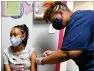  ??  ?? Miriam Araya, 15, looks away as she receives a first dose of the Pfizer vaccine from Melissa Dalton.