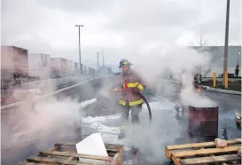  ??  ?? At the B.C. legislatur­e, demonstrat­ors protest legislatio­n forcing postal workers back to work. In Mississaug­a, Ont., a firefighte­r extinguish­es a burning barrel after union groups and activists blocked truck traffic into a Canada Post facility.