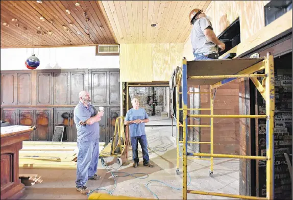  ?? HYOSUB SHIN / HSHIN@AJC.COM ?? Brian (left) and Joe Ward, a manager of Manuel’s Tavern, observe a constructi­on crew at work renovating the beloved bar. The building was stripped to the bones so structural and mechanical improvemen­ts could be made.