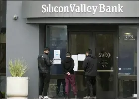  ?? JEFF CHIU — THE ASSOCIATED PRESS ?? People look at signs posted outside of an entrance to Silicon Valley Bank in Santa Clara, Calif., on Friday.