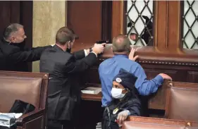  ?? AP PHOTO ?? U.S. Capitol Police with guns drawn stand near a barricaded door as protesters try to break into the House Chamber at the U.S. Capitol on Wednesday in Washington.