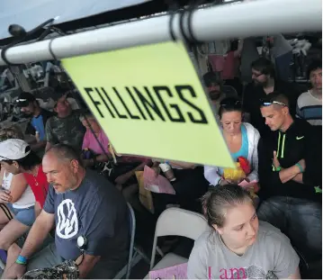  ?? JOHN MOORE/GETTY IMAGES ?? People await dental treatment Saturday as part of a massive free health-care clinic at a county fairground in Wise, Va. The event, held by the charity Remote Area Medical, was staffed by volunteer doctors and nurses, and saw thousands of people without...