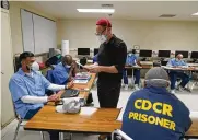  ?? ERIC RISBERG / AP ?? Instructor Douglas Arnwine hands back papers with comments to his incarcerat­ed students during a Mount Tamalpais College English class called Cosmopolit­an Fictions at San Quentin State Prison on April 12.