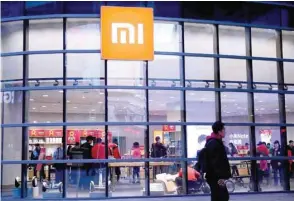  ??  ?? A man walks past a Xiaomi store in Shenyang, China. — Reuters