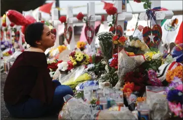  ?? MARIO TAMA — GETTY IMAGES ?? Yamileth Lopez sits while holding a photo of her deceased friend Javier Amir Rodriguez on Aug. 6 at a makeshift memorial for victims near the scene of a mass shooting that left 22 people dead in El Paso, Texas.