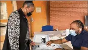  ?? ERIC STIRGUS/ERIC.STIRGUS@AJC.COM ?? William Craig (right) collects informatio­n from Orella Smith, a Morehouse School of Medicine employee, before Smith took a self-administer­ed COVID-19 test on campus.