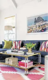  ??  ?? Pops of color and a brass and acrylic coffee table brighten up the living room.