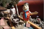  ??  ?? A landscaper passes a Fred Flintstone statue at the iconic Flintstone House in Hillsborou­gh.