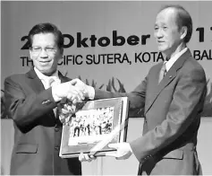  ??  ?? Yong (right) receiving a souvenir from Joannes after officiatin­g at the ‘Kota Kinabalu: A Clean, Green and Liveable City’ seminar.