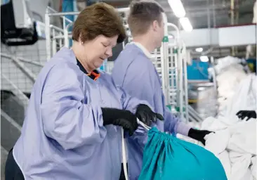  ??  ?? Warragul Linen Service washroom morning supervisor Sue Hammond, sorting through linen where “Charlie Bear” had been found.