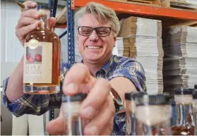  ?? ELAYNE LOWE/THE NEW MEXICAN ?? Colin Keegan, founder of Santa Fe Spirits, helps label bottles of his apple brandy last week. Spirits had an eighth-straight year of U.S. market gains in 2017, according to the Distilled Spirits Council. ‘Whiskey is becoming cool and hip, partly because of the craft movement,’ Keegan said.