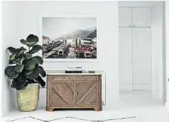  ??  ?? The hallway has been styled with an antique bamboo and marble sideboard as well as a huge pot plant, rug and art.