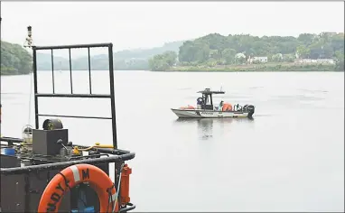  ?? Cassandra Day / Hearst Connecticu­t Media ?? A Middletown police boat patrols the Connecticu­t River at Harbor Park as pyrotechni­cs crews unload fireworks onto a giant barge. Below left, the “pyro crew” haul fireworks and, at right, a Middletown Fire Department truck on hand ensuring safety.