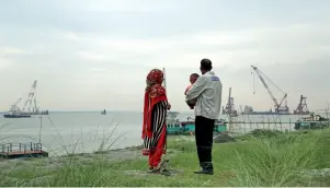  ??  ?? Aux abords du site de travaux du pont Padma au Bangladesh, un homme observe, avec sa fille et son petit-fils, le « pont de leurs rêves » en constructi­on.