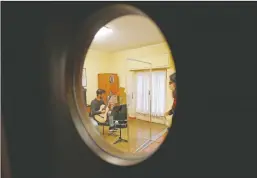  ??  ?? Carlo D’Ariano is seen through a window as he plays his guitar behind a transparen­t panel during a lesson with maestro Maria Vittoria Jedlowski.