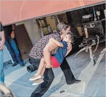  ?? CORY MORSE | MLIVE.COM THE ASSOCIATED PRESS ?? A woman carries a child into the U.S. Immigratio­n and Customs Enforcemen­t building in Grand Rapids, Mich. More than 2,000 immigrant children were reportedly separated from their parents.